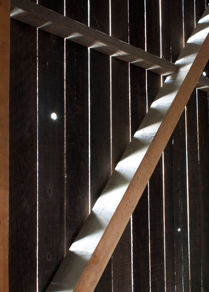 Light beams coming through the boards of an old barn wall